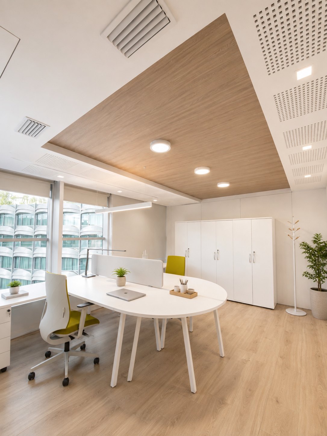 Corner office: an oval meeting table under an oak-veneered ceiling raft with three circular fittings, white fitted storage alongside