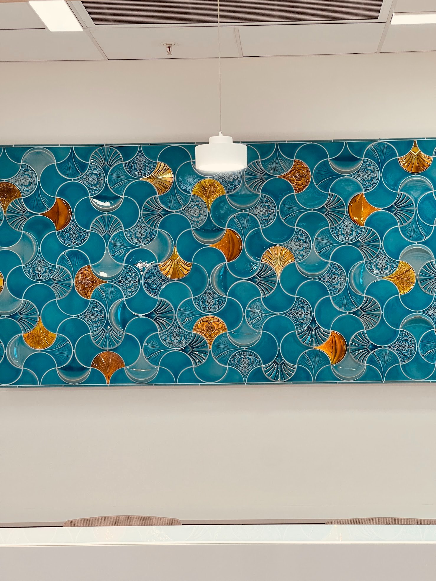 A celadon-glazed Zsolnay ceramic wall with gold-lustre ginkgo motifs in the reception of a Shanghai office